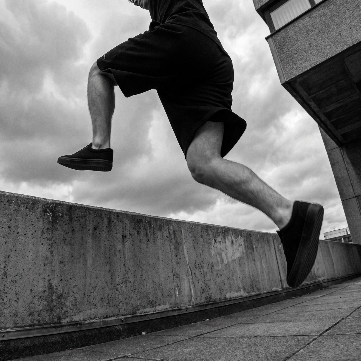 Rider mid-vault over a concrete ledge in black AFS shorts